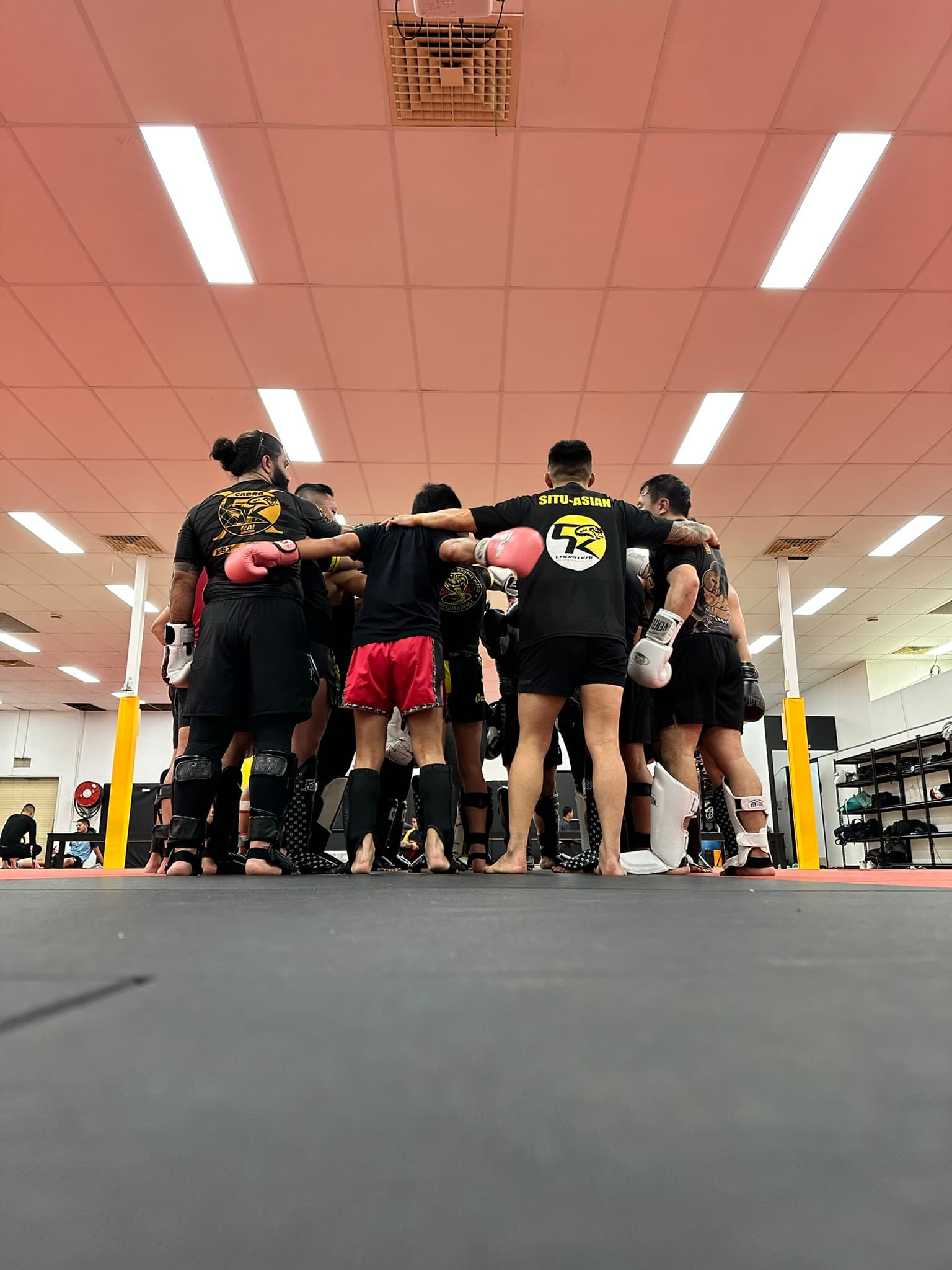 The class in a huddle on the mats after training
