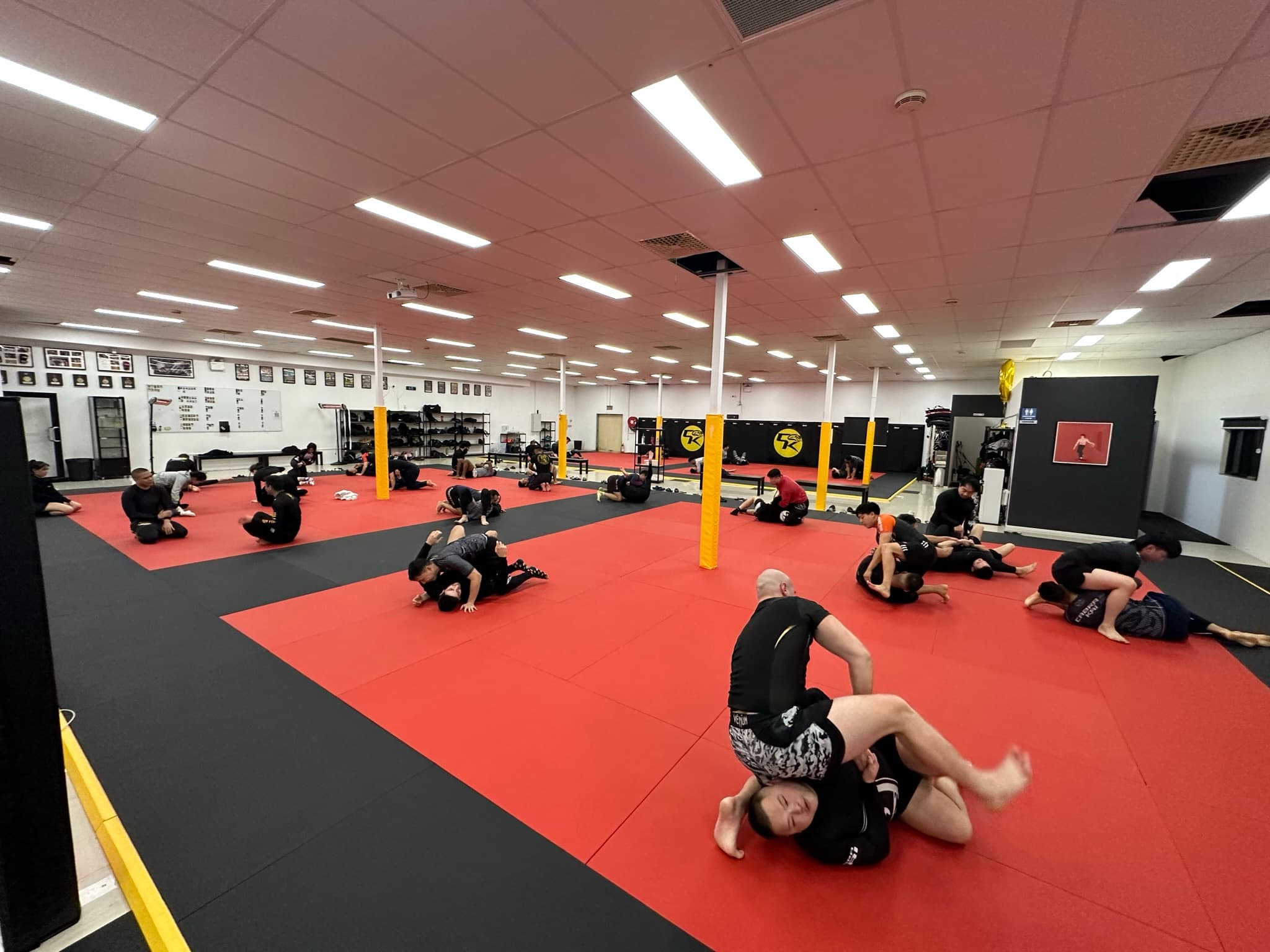 A full jiu-jitsu class rolling on the red and black mats