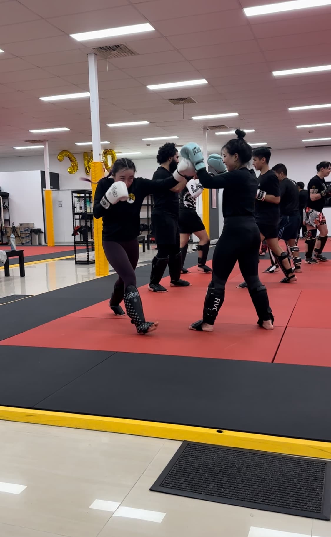 Two members exchanging punches in gloves and shin guards